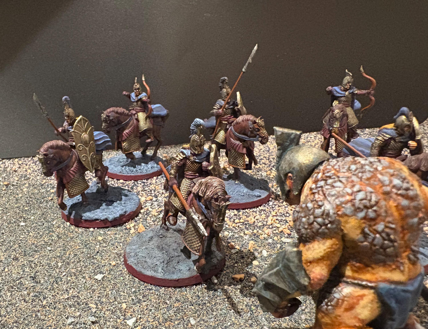 dynamic image of elf horsemen miniatures charging a stone troll miniature