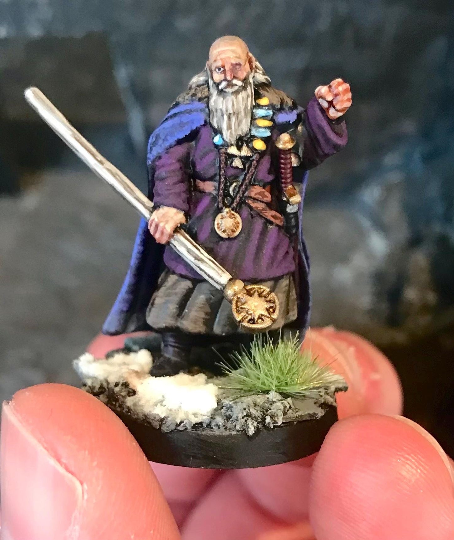 Miniature dark fantasy figurine of a wizard holding a staff on a dark background