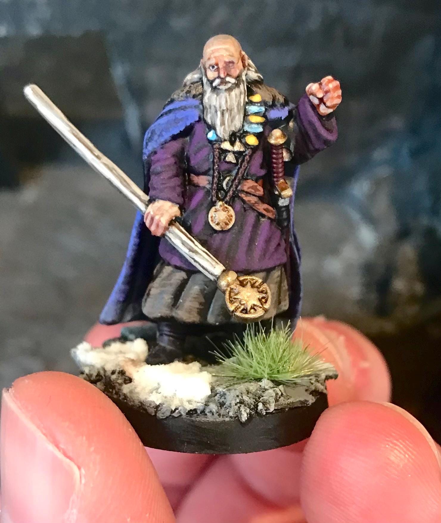 Miniature dark fantasy figurine of a wizard holding a staff on a dark background